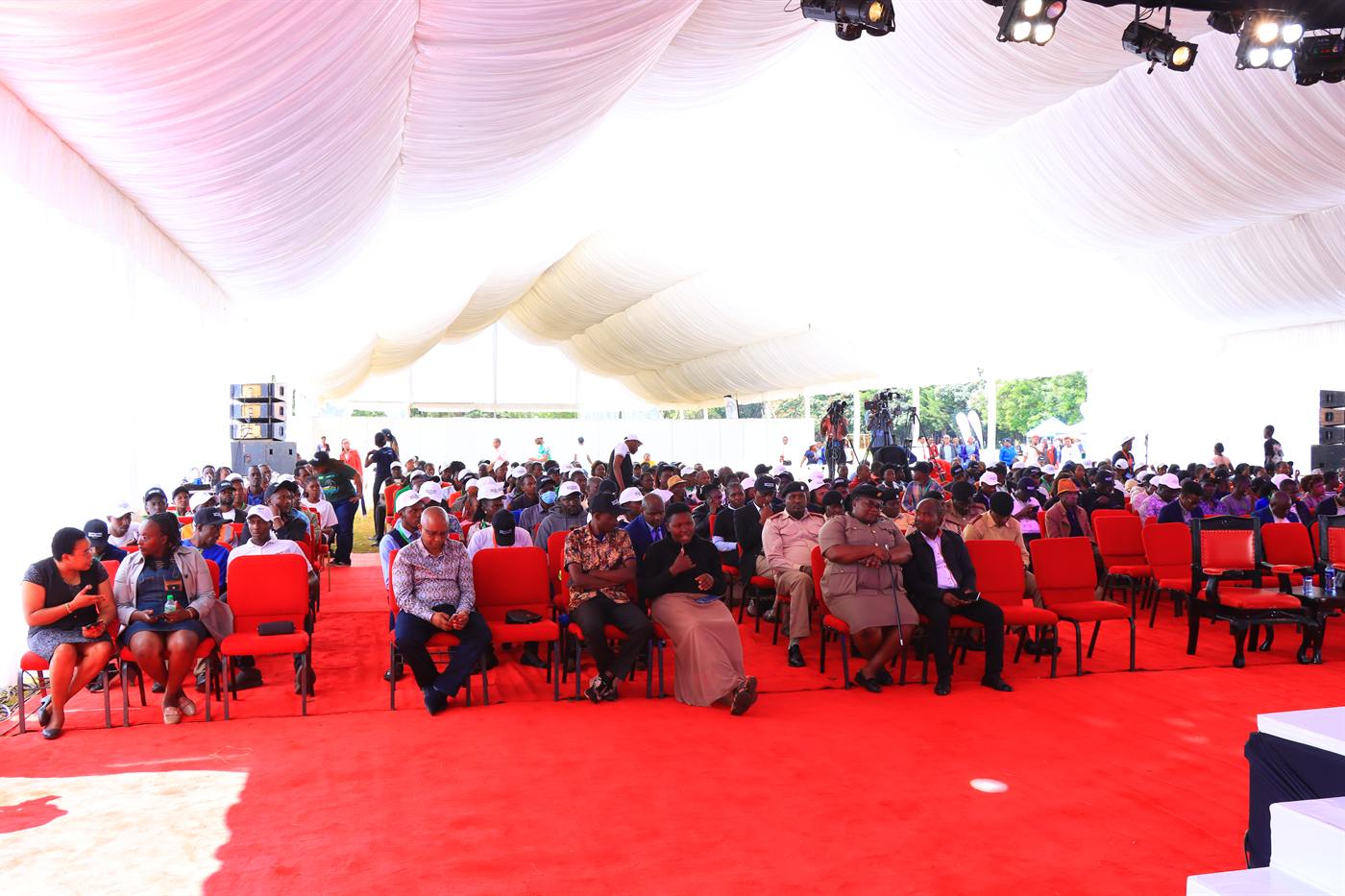 A large audience seated under the white festival tent