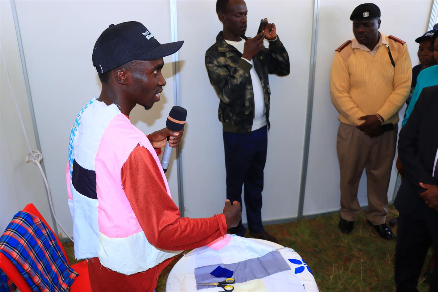 A young man presenting with a microphone at an outdoor booth