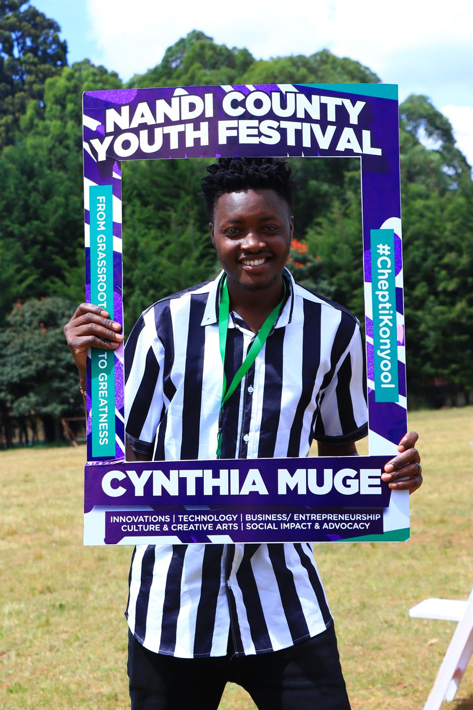 A young man smiling through the Nandi County Youth Festival photo frame