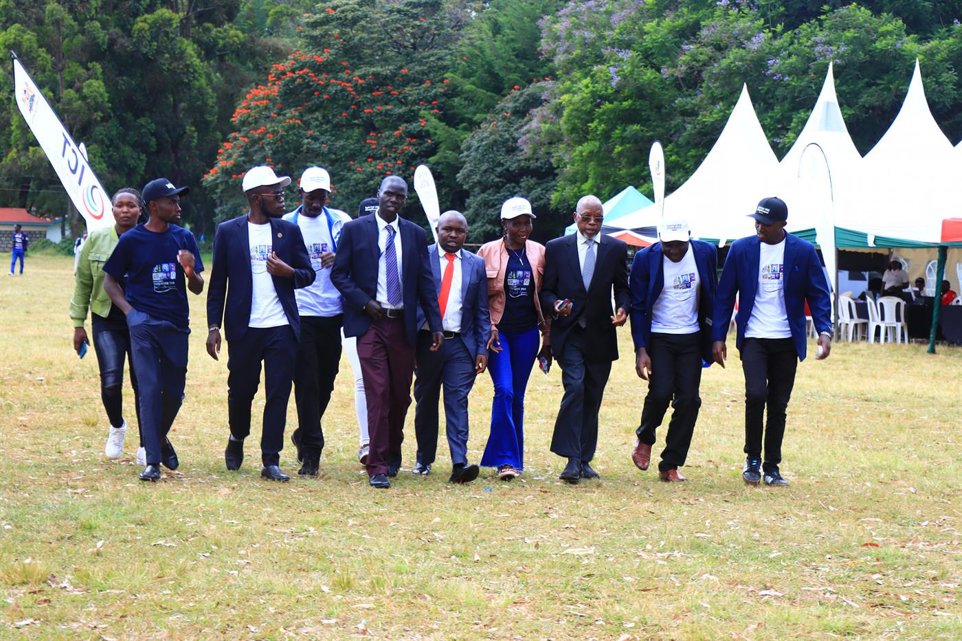 A group walking across the festival grounds past white tents